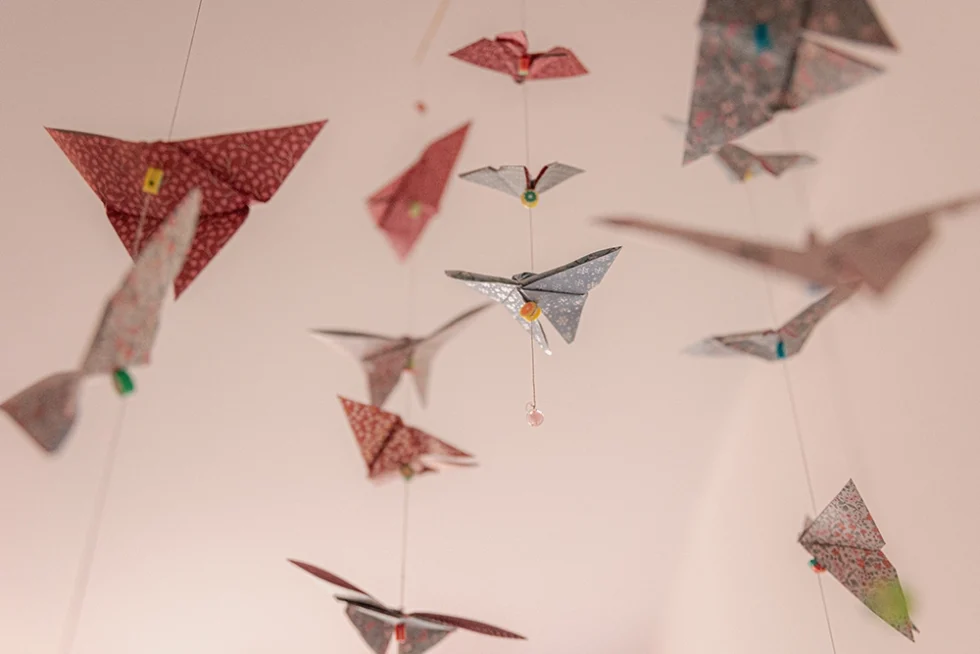 Suspensions multicolores de type avion en papier ou papillon accrochées au plafond.