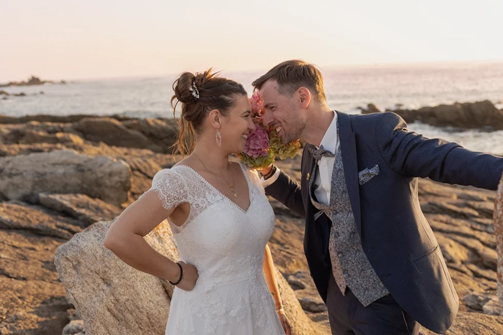 Jeunes mariés sur les rochers en bord de mer.