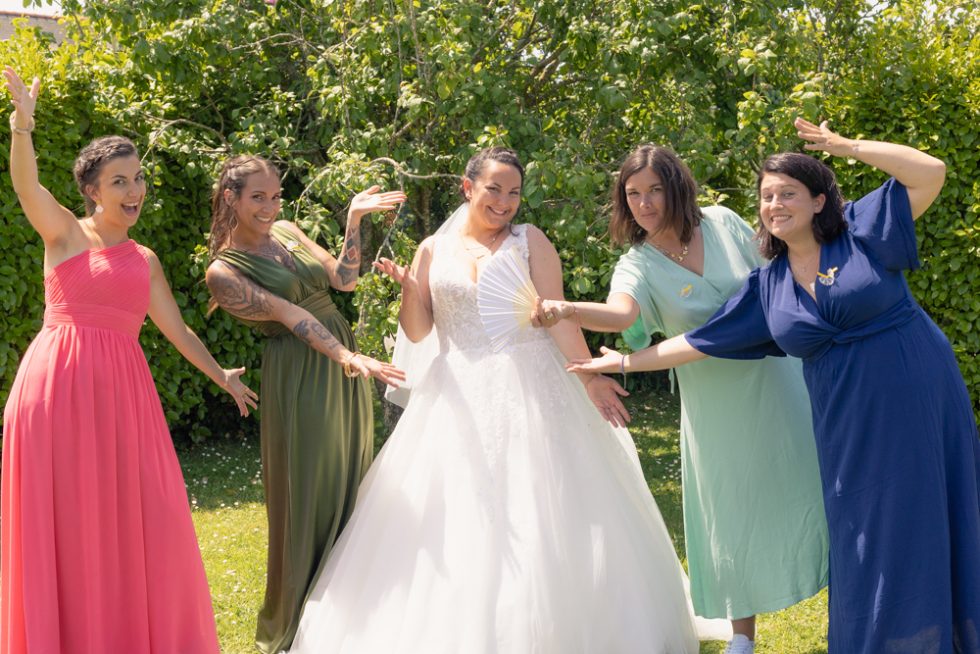 La mariée et ses témoins posent de façon décontractée dans un jardin